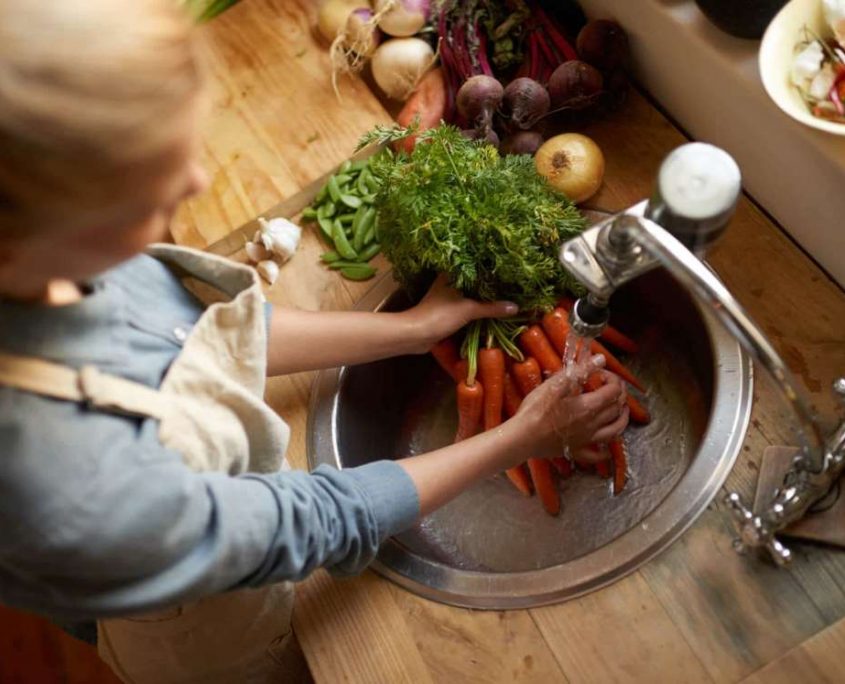 Lavaggio verdure con acqua depurata - GB Depura - Twister Adv Donna che lava carote fresche sotto l'acqua corrente del rubinetto della cucina per GB Depura.
