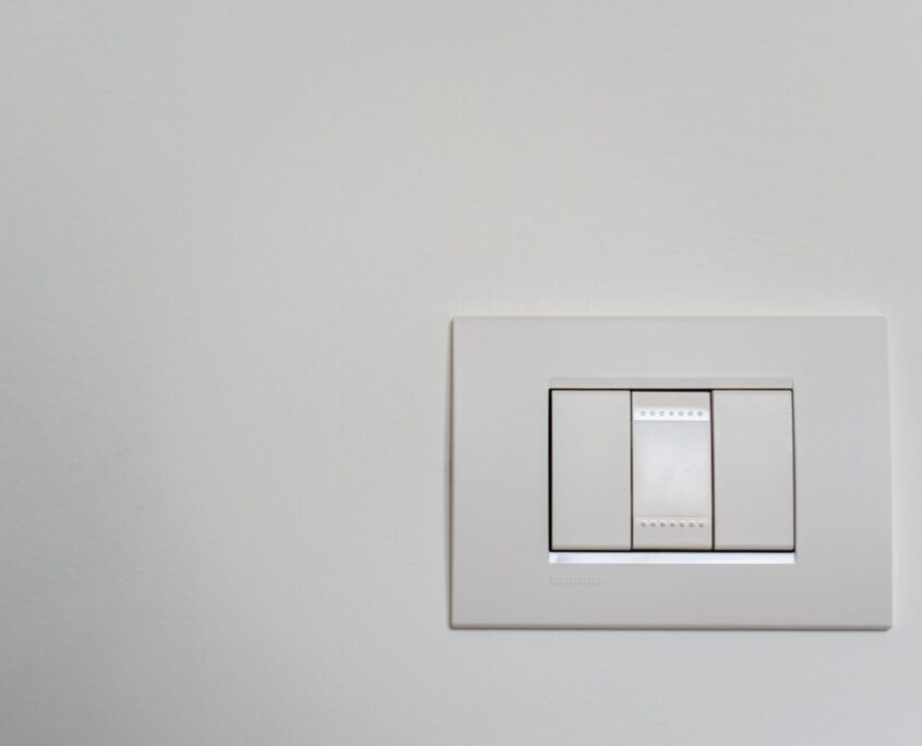 Elettrici Group - Impianti e Materiale Elettrico - Sito, Social e Grafica Placca e interruttore elettrico di design montato su parete bianca, Elettrici Group
