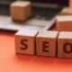 Cubetti di legno con la scritta SEO e computer portatile sullo sfondo per l'ottimizzazione SEO del sito web