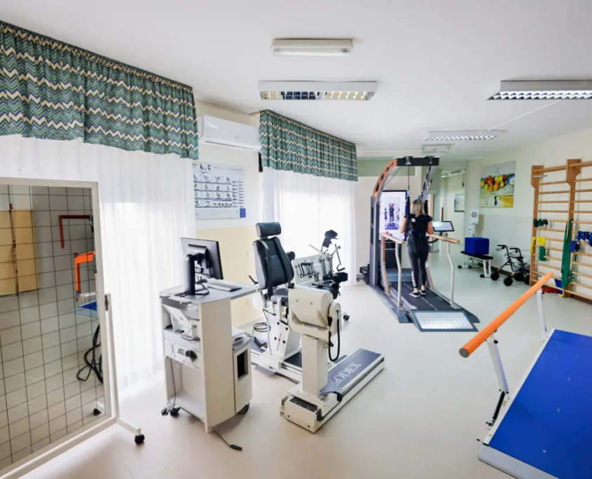 Centro di Fisioterapia e Riabilitazione Motoraria - Parisan Catanzaro Sala di fisioterapia e riabilitazione del centro Parisan attrezzata con spalliera in legno, tapis roulant per rieducazione motoria, parallele e macchinari elettromedicali avanzati.